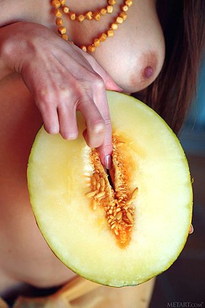 Topless sarong-wearing beauty suggestively fingering the fruit