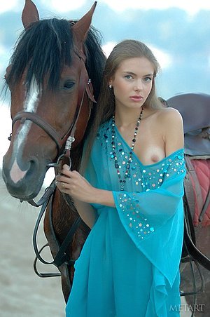 Horse girl posing next to a wild stallion in a outdoor erotic shoot